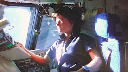 Sally Ride monitorea los paneles de control desde la silla del piloto en la cubierta de vuelo, frente a un cuaderno de procedimientos de vuelo.