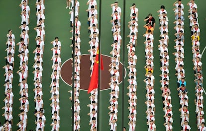 Niños haciendo cola para una ceremonia de izamiento de bandera en su primer día de regreso a la escuela después de las vacaciones de verano, en el patio de una escuela secundaria en Shanghái (China).