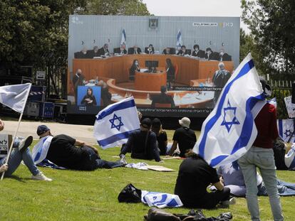 Manifestantes israelíes siguen las deliberaciones del Supremo sobre Netanyahu en una pantalla, este domingo en Jerusalén.