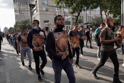 Jóvenes marchan en fila con carteles con el monumento a la Revolución de fondo.