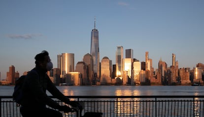 Homem pedala por uma rua deserta diante do ‘skyline’ de Manhattan.