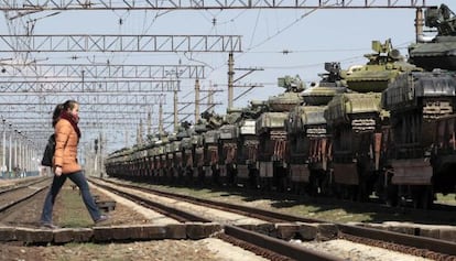 Una mujer cruza una v&iacute;a de tren junto a tanques ucranios cargados en plataformas para ser trasladados desde Crimea a otras regiones. 