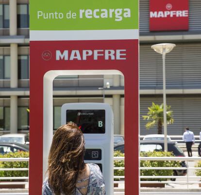 Una joven utiliza uno de los puntos de recarga de coches eléctricos.