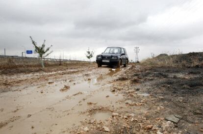 Uno de los residentes de la urbanización El Avalón, en Paracuellos del jarama, conduce por el camino embarrado de acceso a las viviendas.