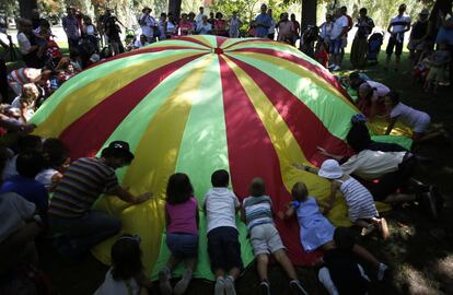Un grupo de niños se abalanza sobre una lona de colores.