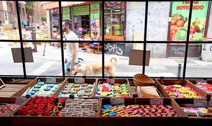 Un chico pasea con un perro delante de una pastelería canina en Madrid.