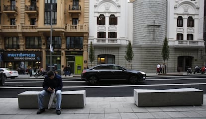 Un viandante descansa en uno de los nuevos bancos que se han instalado en las aceras de la Gran Vía.