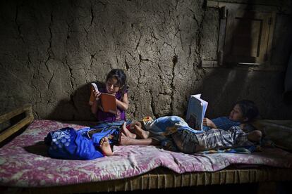 Tres hermanos aún por escolarizar aprenden a leer en casa con los libros de texto de una hermana mayor.  