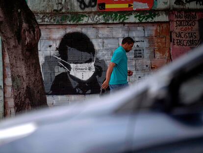 Homem caminha diante de grafite do presidente Bolsonaro, no Rio.