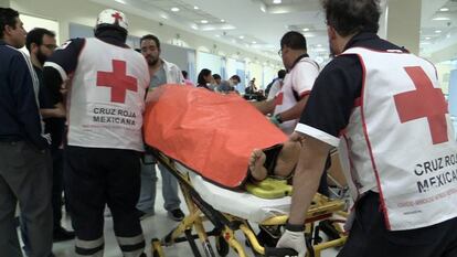 Los paramédicos de la Cruz Roja trasladan a un herido.