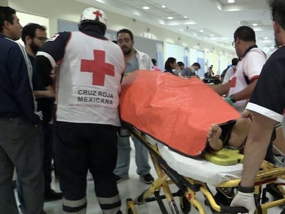 Los paramédicos de la Cruz Roja trasladan a un herido.