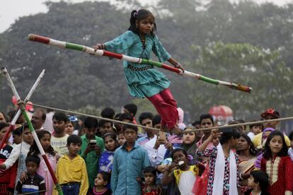 Una multitud observa a Rani, de 7 años, realizar un ejercicio de equilibrio en un parque público en Calculta (India).