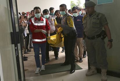 Agentes de policía y miembros de la Cruz Roja Indonesia portan uno de los cadáveres que ha dejado el accidente de autobús este sábado en Java.