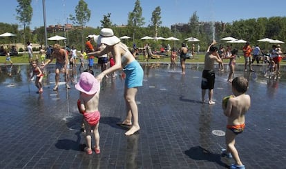 Niños y adultos se refrescan en una fuente de Madrid.