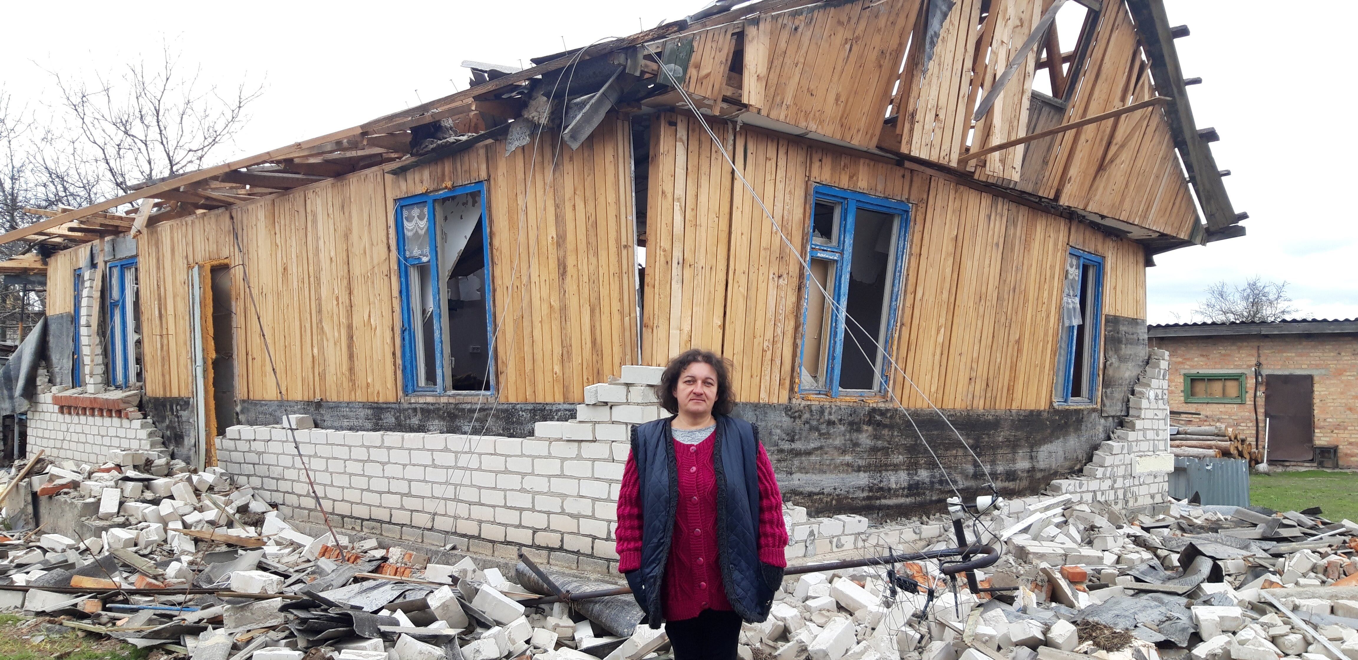 Natalia Ribachok, frente a su casa semiderruida por el impacto de un proyectil.