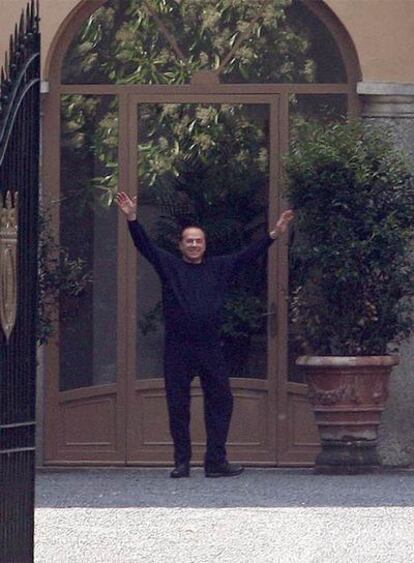 Berlusconi saluda a los fotógrafos el domingo a la puerta de su residencia en las afueras de Milán.