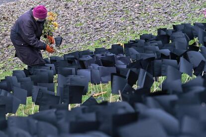 Una anciana coloca flores delante de miles de banderas de papel negro colocadas por activistas del partido político de la oposición Coalición Democrática, en homenaje a las personas que murieron durante la pandemia de coronavirus (covid-19), en Budapest (Hungría).