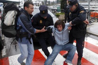 Dos policías intentan sacar a un joven argentino del vial de la T-1 en Barajas (Madrid).