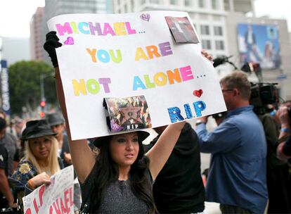 Una joven enseña un cartel donde se lee 'Michael no estás solo', en las afueras del Staples Center