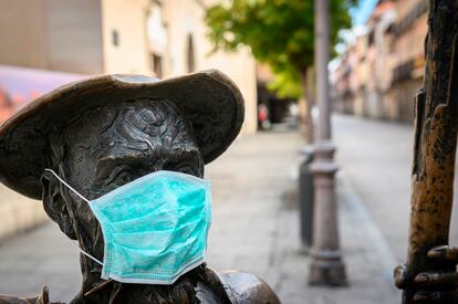 Estatua de Don Quijote con una mascarilla frente a la Casa Natal de Miguel de Cervantes en Alcalá de Henares.