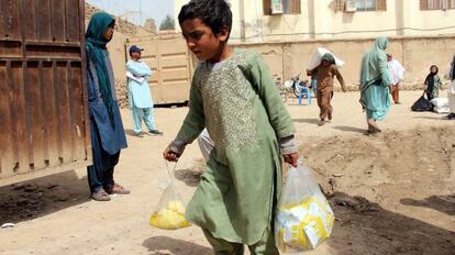 Un niño sostiene bolsas con ayuda entregada a varias familias afganas afectadas por inundaciones, en Kandahar.