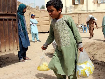Un niño sostiene bolsas con ayuda entregada a varias familias afganas afectadas por inundaciones, en Kandahar.