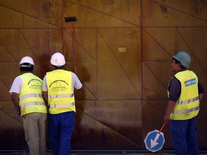 Varios obreros de la construcción pintan una chapa en una obra en el centro de Madrid.