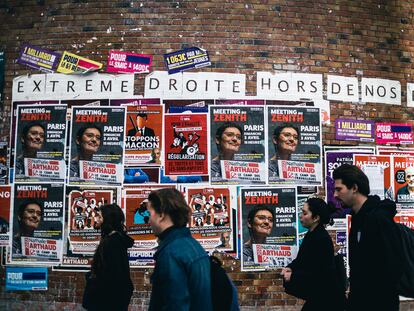 Jóvenes estudiantes pasan por delante de propaganda electoral sobre un muro de la universidad de Tolbiac en París