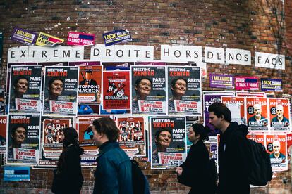 Jóvenes estudiantes pasan por delante de propaganda electoral sobre un muro de la universidad de Tolbiac en París