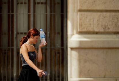 Una mujer caminaba el 10 de agosto en Valencia con una botella de agua fría.