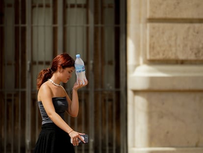 Una mujer caminaba el 10 de agosto en Valencia con una botella de agua fría.