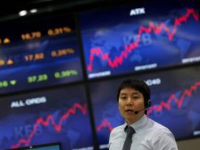 Un corredor de bolsa trabaja junto a unos monitores que ofrecen la información bursátil en Seúl. EFE/Archivo