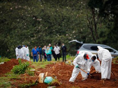 Trabalhadores enterram uma vítima de covid-19 nesta quinta-feira no Cemitério Viola Formosa, em São Paulo (Brasil).