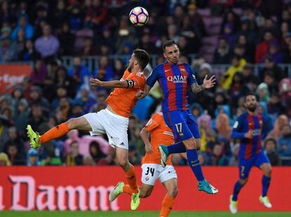 El delantero del Barcelona Paco Alcácer salta a por el balón con el defensa del Osasuna Oier.