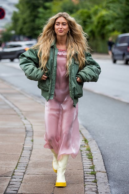 Emili Sindlev, una de las influencers nórdicas más conocidas, cambia por completo un suntuoso vestido de aires lenceros sumándole chaqueta bómber verde militar y botas de goma.