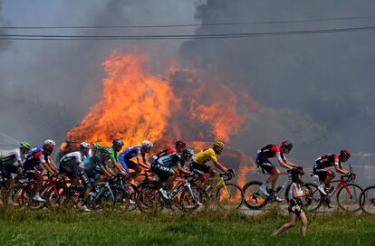 El pelotón ciclista pasa al lado de unas balas de heno en llamas durante la etapa 6ª, entre Brest y Mur-de-Bretagne Guerleden, el 12 de julio de 2018.