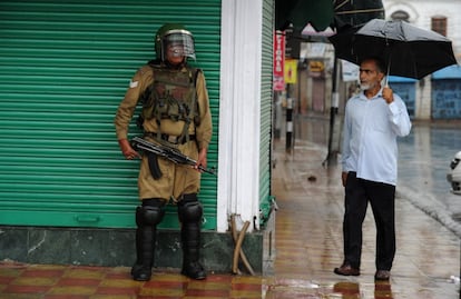 Un musulmán de Cachemira observa a un soldado paramilitar indio haciendo guardia en medio de una fuerte lluvia durante el toque de queda en Srinagar, India.