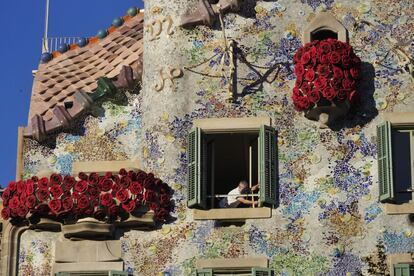 Un treballador en una de les finestres de la Casa Batlló engalanada de roses pel dia de Sant Jordi.