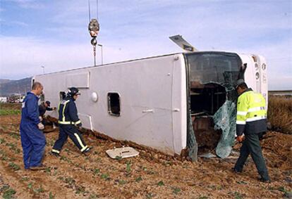 Una grúa se dispone a retirar el autobús sinistrado en Totana de un campo de cultivo.