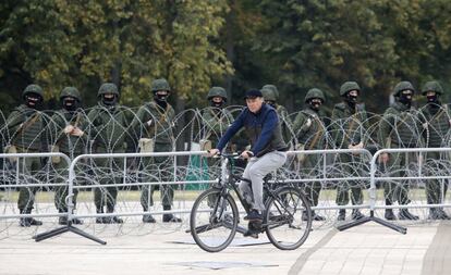 Un hombre pasa con su bicicleta cerca de militares que bloquean una calle de la capital, antes de la llegada de los manifestantes a la zona.