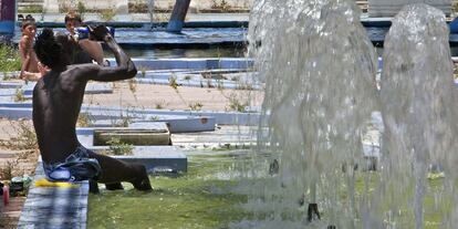 Una persona se refresca por el calor en una fuente de Sevilla.