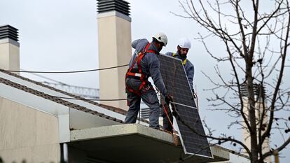 Dos técnicos instalan paneles solares en Madrid.