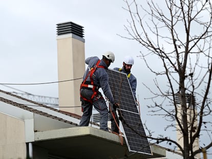 Dos técnicos instalan paneles solares en Madrid.