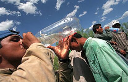 <i>Ilegales</i> mexicanos beben agua ofrecida por los policías tejanos que acaban de detenerlos, en julio.