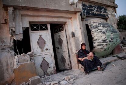 Los observadores de Naciones Unidas han entrado este domingo en la localidad de Treimse para ver las consecuencias del ataque del pasado jueves por las fuerzas de El Asad. En la imagen, una mujer sostiene a su nieto en brazos a las puertas de su casa, afectada por los bombardeos y prácticamente destruida.