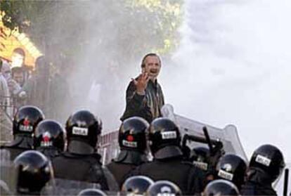 Un manifestante unionista increpa a los antidisturbios mientras resulta alcanzado por un cañón de agua.