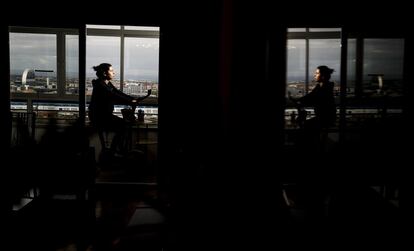 Julieta monta en bici estática en una terraza acristalada desde donde se ve el madrileño barrio de Las Tablas.