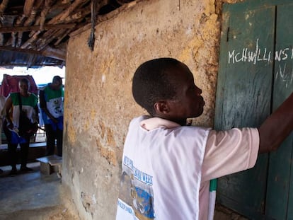 El enfermero comunitario Lansana Lavalie escribe en la fachada de una casa el número de mosquiteras que ha repartido en ella durante una campaña nacional de distribución en Gondama, Sierra Leona, en junio de 2017.