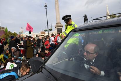 Un hombre conduce un coche fúnebre mientras los activistas de la Rebelión de la Extinción se reúnen en Trafalgar Square de Londres.