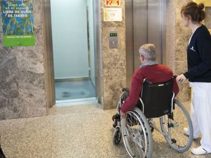 Una enfermera traslada a un paciente en silla de ruedas.